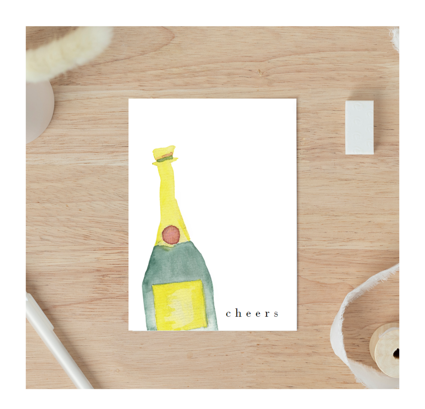 A greeting card featuring a watercolor illustration of a champagne bottle with the word "Cheers" elegantly displayed. The design is colorful and festive, making it suitable for various celebratory occasions such as birthdays, weddings, engagements, promotions and graduations. 1 