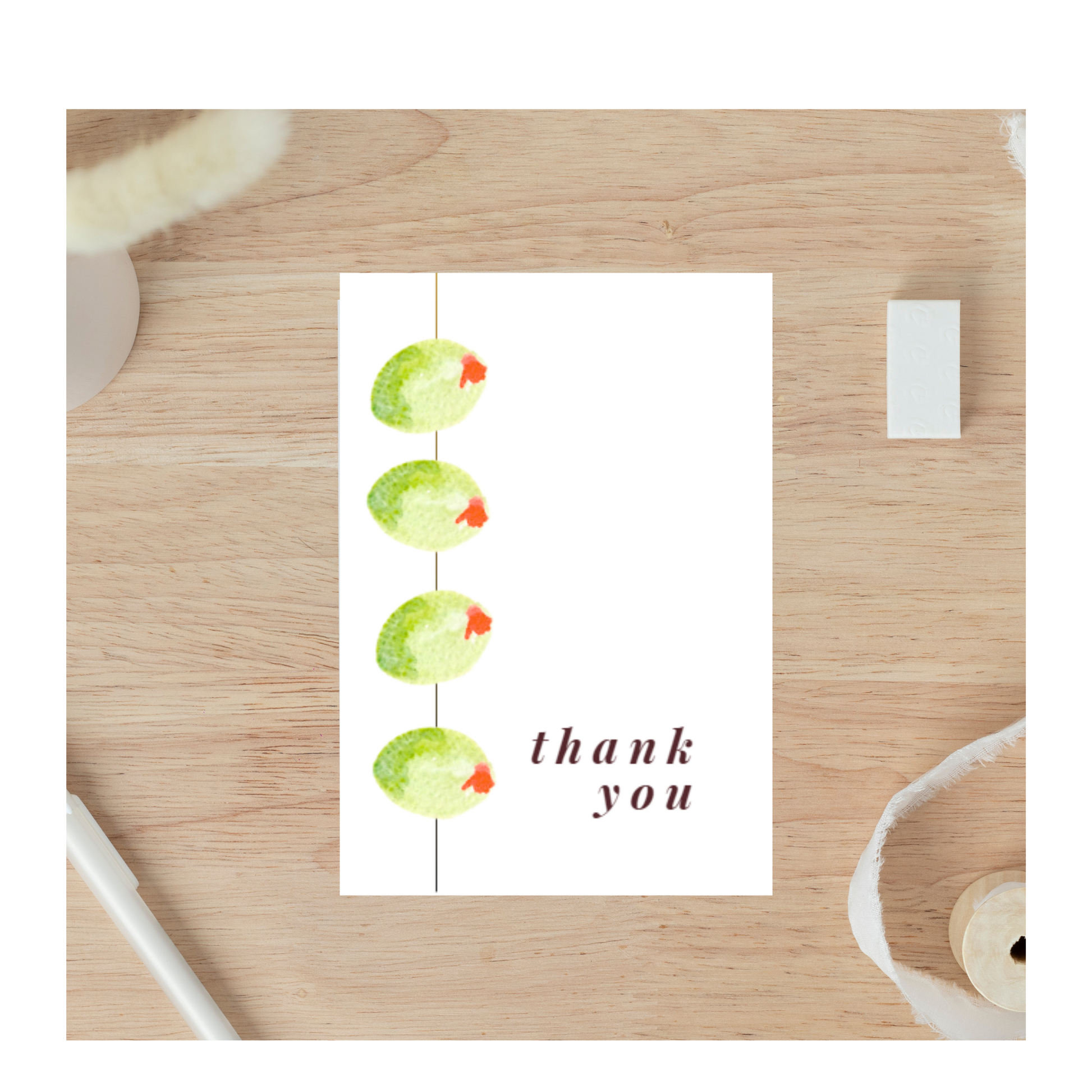 A thank you card featuring a delicate watercolor illustration of olives on a stick, with soft green and purple tones. The design is elegant and inviting, perfect for expressing gratitude. The card has a simple, blank interior for personal messages.